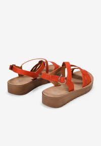 Sandalias de plataforma naranjas con correas texturizadas, un hebilla ajustable y una plantilla suave con detalles de costura.