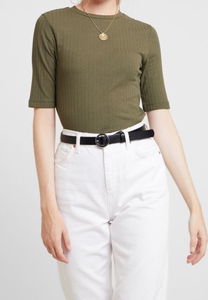 Haut à manches courtes côtelé vert olive associé à un jean blanc taille haute et une ceinture noire avec une boucle circulaire.