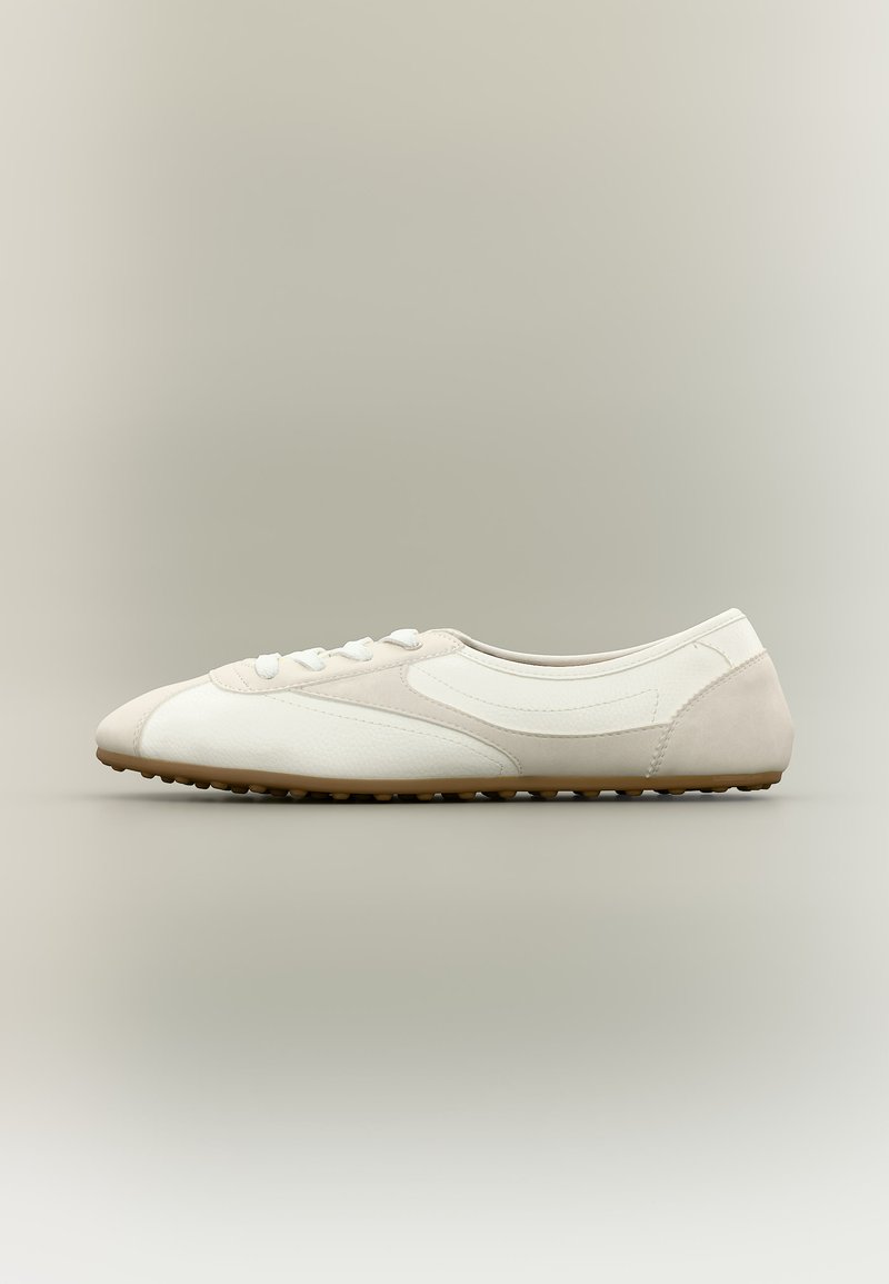 Λευκό sneaker χαμηλού προφίλ με μπεζ λεπτομέρειες και λαστιχένια σόλα, ορατό από το πλάι σε ουδέτερο φόντο.