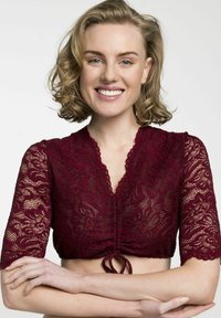 Burgunderfarbenes Spitzen-Crop-Top mit kurzen Ärmeln, floralem Muster, tiefem V-Ausschnitt und gebundenem Frontdetail. Die Textur wirkt zart und transparent.