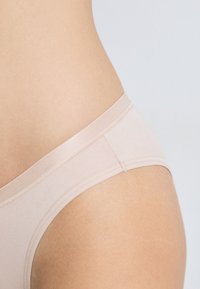 Light beige cotton underwear with a soft, elastic waistband and smooth texture, featuring minimal stitching and a sleek design.
