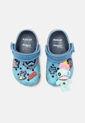 Børns blå Crocs med Disney Stitch-tema charms og en blød voodoo dukke fastgjort til højre skos rem.