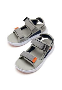 Sandales grises avec deux brides ajustables en velcro, un dessus texturé et une semelle blanche. Présente un petit accent orange sur une des brides.
