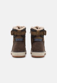 Stivali ankle in pelle marrone e tessuto con fodera in pelliccia sintetica, dettagli con fibbie e suola in gomma texture, caratterizzati da un design alla moda.