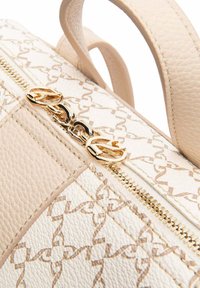 Borsa a tracolla in pelle beige con superficie testurizzata, dotata di un cursore della cerniera a catena dorata e un discreto motivo a catena su uno sfondo più chiaro.