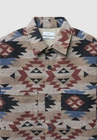 Camicia tessuta con un motivo geometrico marrone, nero e blu. Presenta un colletto, due tasche frontali e bottoni neri. Realizzata in tessuto strutturato.