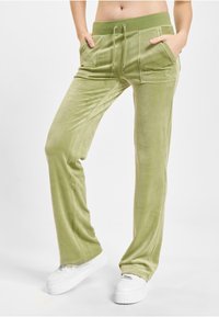 Jasnozielone dresowe spodnie z weluru z dwiema przednimi kieszeniami, elastycznym pasem i regulowanym sznurkiem. Charakteryzują się gładką fakturą i luźnym krojem.
