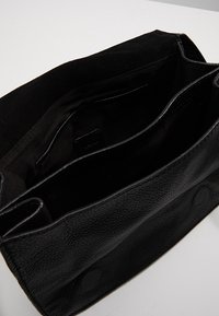 Borsa a mano in pelle nera aperta per mostrare due scomparti principali e una tasca interna con rivestimento in tessuto.