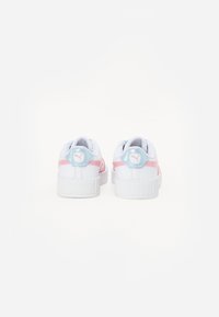 Des baskets blanches avec une épaisse semelle blanche, dotées d'accents roses et d'un patch de talon bleu clair avec un logo. Texture lisse, design minimal.