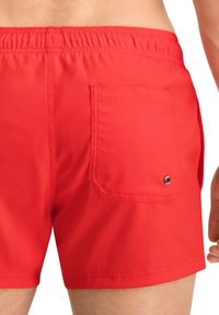 Rote Schwimmshorts aus glattem Stoff mit einem elastischen Bund und einer hinteren Pattentasche mit einem runden Logo-Akzent.