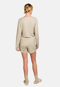 Helles beige Loungewear-Set mit langen Ärmeln und Shorts in einem geometrischen Muster. Das Material wirkt weich, mit einem elastischen Bund und Bündchen.