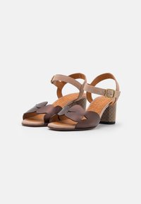 Braune Leder-Absatzsandalen mit durchbrochenem Blumenmuster, beigem Knöchelriemen, strukturiertem Fußbett und gemustertem Blockabsatz.