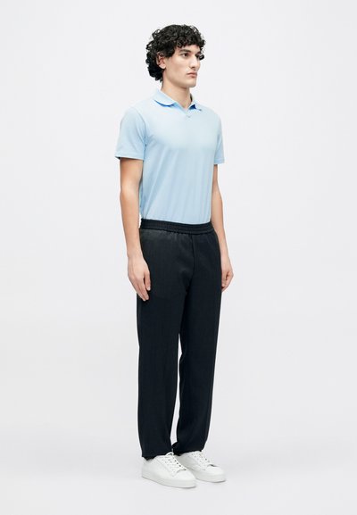 Hele sinine lühikeste varrukatega polo särk, kombineeritud mustade elastse vöökohaga pükstega ja valgete tossudega. Lihtne disain ning mugav lõige.