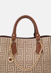 Sac à main beige avec motif géométrique et accents en cuir marron. Doté de quincaillerie dorée, de détails en chaîne et de deux poignées supérieures.