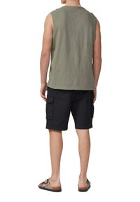 Olijfgroene mouwloze top met een losse pasvorm, gecombineerd met zwarte cargo shorts met zijzakken, en bruine sandalen.