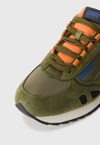 Green suede and mesh sneaker with orange laces, blue accents, textured sole, and padded tongue. Features cut-outs on the sides.