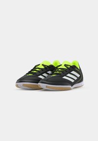Scarpe da ginnastica nere con strisce bianche e dettagli giallo neon. Presentano una tomaia liscia, lacci e una suola in gomma.