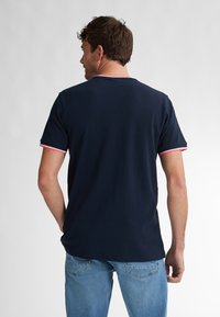 Mörkblå kortärmad T-shirt med kontrasterande rosa och vita ribbade detaljer vid kragen och ärmarna. Mjuk material och standard passform.