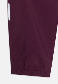 Manga de chaqueta impermeable color marrón con dobladillo elástico, que presenta una franja reflectante en el lateral para mayor visibilidad. Textura suave, material ligero.