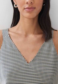 Schwarz-weiß gepunktetes Kleid mit V-Ausschnitt, aus leichtem Stoff gefertigt. Verfügt über breite Schulterträger und eine glatte Textur.