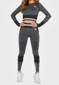 Černá a šedá sportovní souprava, která zahrnuje zkrácenou dlouhý rukáv vršek a legíny s vysokým pasem, zdobené texturovanými vzory a kontrastními pruhy.
