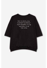 Czarny rozmiar oversize sweter z okrągłym dekoltem i krótkimi rękawami. Z tyłu znajduje się biały tekst z inspirującym cytatem.