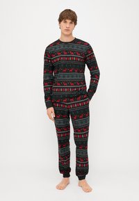 Long-sleeve black pajama set featuring a festive reindeer and snowflake pattern in red, green, and gray. Soft fabric with elastic cuffs and waistband.