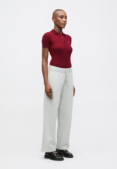 Burgundijas ribota polo krekls, pelēki platleņu sporta bikses un melni loaferi. Gluda tekstūra, ikdienas formas, ar apkakli un regulējamu jostasvietu.