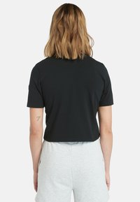 Černé zkrácené tričko s krátkými rukávy, vyrobené z hladké látky. Má kulatý výstřih a jednoduchý, minimalistický design.