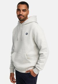 Felpa grigia chiara con tasca a marsupio, cappuccio con coulisse e un logo circolare blu navy sul lato sinistro del petto. Tessuto morbido e con texture.