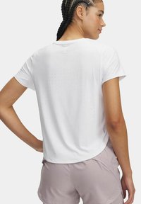 Camiseta atlética blanca de manga corta, con pequeñas perforaciones en la parte posterior para ventilación, combinada con pantalones cortos de color púrpura claro.
