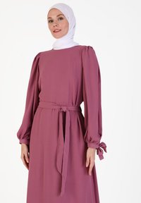 Long-sleeve, rose-colored dress with a belted waist and gathered cuffs. Made from soft fabric, features a simple, elegant design.
