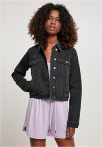 Zwarte denim cropped jack met een knoopsluiting aan de voorkant, twee borstzakken en een effen kleur. Draagt over een lichtpaarse jurk.