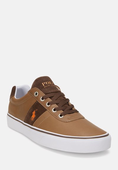 Καφέ δερμάτινα αθλητικά παπούτσια με σουέτ λεπτομέρεια, λευκή καουτσούκ σόλα, στρογγυλή μύτη και καφέ κορδόνια. Διαθέτουν λογότυπο και μεταλλικά οπές.