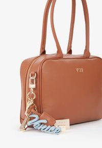 Sac en cuir marron de forme rectangulaire, avec des accessoires en or, des poignées doubles et un charme bleu "Venise" attaché à la tirette de la fermeture éclair.