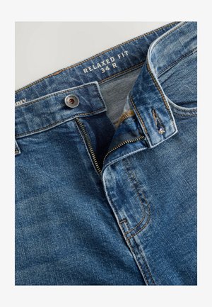 Jeans de denim azul de corte relajado con cremallera, que cuentan con cierre de botón de metal y costuras en contraste. Patrón de desgaste visible en la tela.