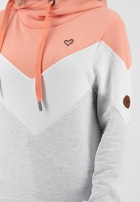 Felpa con un design a pannelli di colore, con sezioni corallo, bianche e grigie. Tessuto morbido, cordino regolabile e dettaglio del logo a forma di cuore.