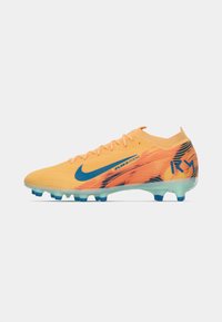 Nike focicipők élénk narancs és kék dizájnnal, texturált felsőrésszel és átlátszó talppal, kék stoplikkal a tapadásért.
