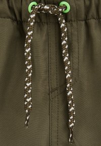 Oliviroheline kangas tekstuurse pinnaga, millel on pruunide ja valgete punutud paeltega lukustusnöör, mis kinnitatakse erkroheliste silmadega.