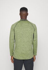 Langsleeve groene sportshirt gemaakt van textuurstof, met zwarte accenten en een gele merkcol.