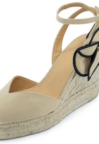 Sandalo wedge in canvas beige con suola in juta intrecciata, apertura a forma di V, cinturino alla caviglia regolabile e dettaglio floreale nero a contrasto.