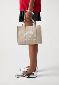 Borsa tote beige con stampa bianca "KARL LAGERFELD PARIS 21 RUE ST-GUILLAUME." Materiale in cotone, forma strutturata e manici corti.