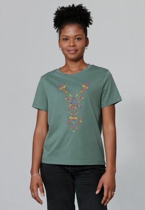 T-shirt en coton vert avec un col rond et des manches courtes, présentant une broderie florale colorée dans un design symétrique sur le devant.