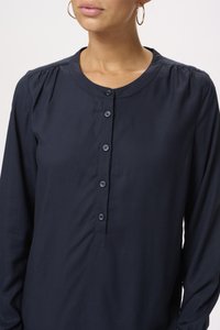 Blusa de manga larga azul marino en tejido suave, con cuello redondo, cierre frontal con botones y detalle de hombros plisados.