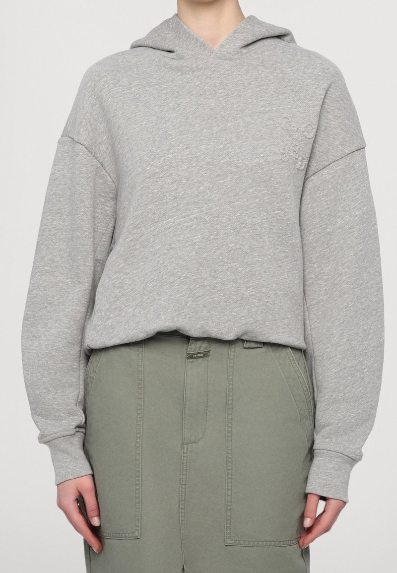 Sudadera gris hecha de una tela suave, con un ajuste relajado, mangas largas y un bolsillo frontal, combinada con pantalones cargo verdes.