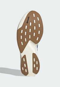 Sneaker sole featuring a white base, textured brown rubber outsole with circular and rectangular cutouts, and a logo detail embedded.