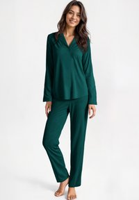 Set di pigiama verde scuro realizzato in tessuto morbido. Maglietta a maniche lunghe con bottone e colletto, abbinata a pantaloni con vestibilità rilassata.