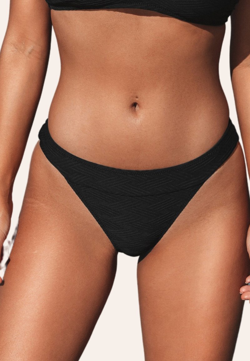 Bas de maillot de bain noir avec un motif en zigzag texturé. Présente une coupe taille basse et de larges bandes latérales, fabriqué en matériau doux et élastique.