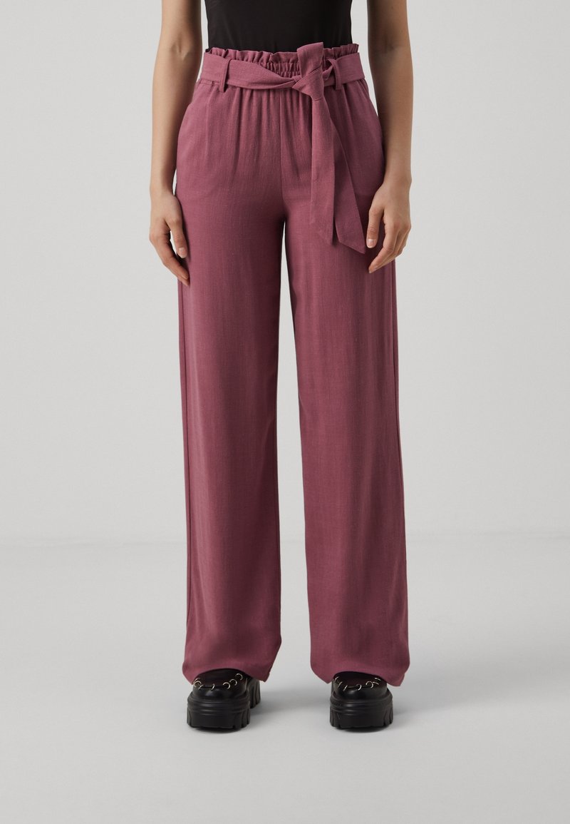 Pantalon à jambes larges en tissu rose profond, doté d'une taille élastiquée et d'une ceinture nouée. Texture lisse avec poches latérales.