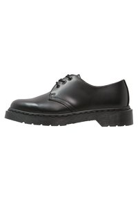 Scarpa nera in pelle con lacci, punta rotonda e suola in gomma texturizzata, caratterizzata da dettagli di cucitura lungo il bordo della suola.